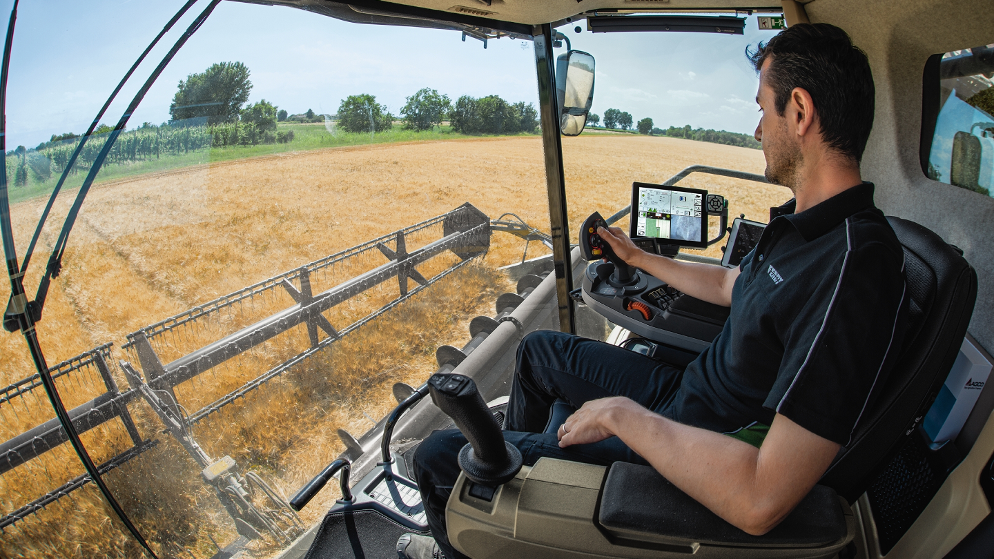 Man collecting data via software while driving combine 