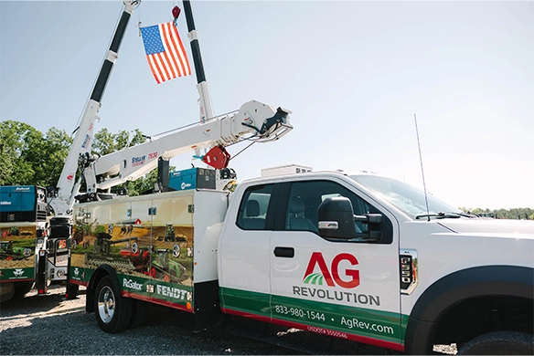 AgRevolution mobile service truck equipped with a service crane and displaying Fendt and RoGator branding, ready to provide same-day field support; American flag hoisted above symbolizes pride in local service.