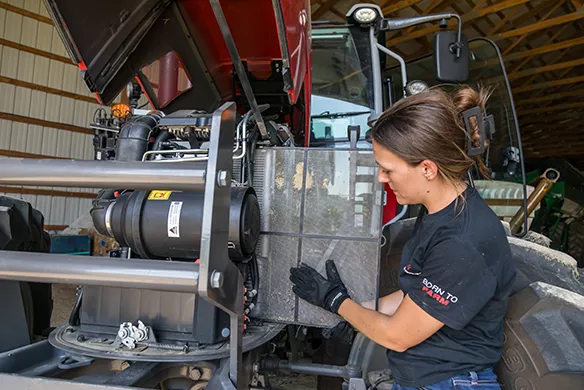 Woman inspecting MF 5M series AGCO Parts filter for preventative maintenance service.